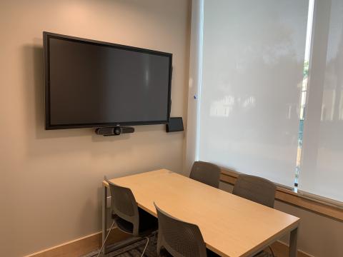Image of study room 1A showing a table with four chairs and a large screen and control panel mounted on the wall.