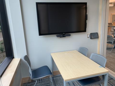 Image of Study Room 1C showing three chairs around a table with a large screen and control panel mounted on the wall.