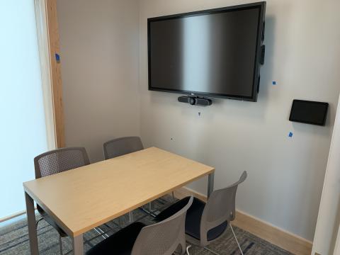 Image of Study Room 2A showing a table with four chairs and a screen with a control panel mounted on the wall.