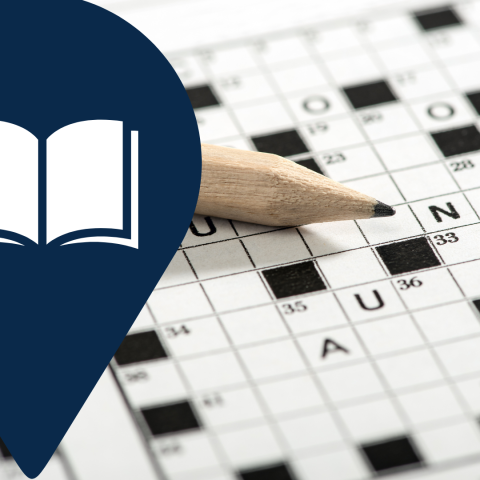 A crossword puzzle with a pencil laying across it